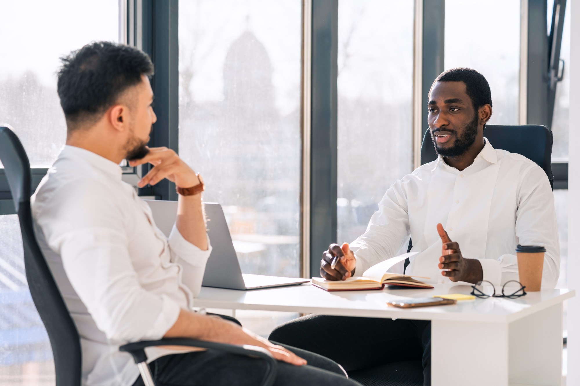 Two leaders in conversation across a desk in a bright office